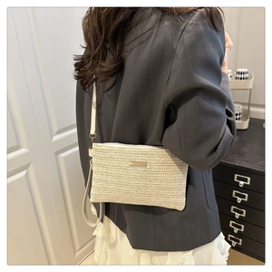 Detail of a beige woven crossbody bag showing intricate texture and metal hardware logo