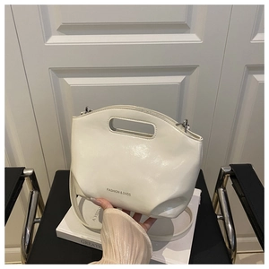 Gros plan d'un sac à main en cuir verni blanc crème avec lettrage et finitions argentées