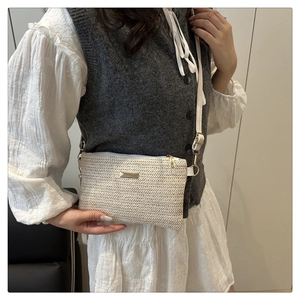 Detail of woven texture and golden metal clasp on minimalist beige crossbody bag