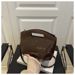 Détail du sac seau en cuir verni marron foncé avec poignée creuse et bandoulière