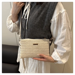 Detailed view of cream woven crossbody bag featuring a golden metallic buckle and texture
