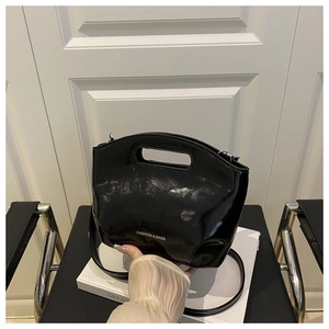Détail d'un sac bandoulière en cuir verni noir avec logo texte mode blanc