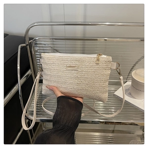 Detail of V-shaped woven texture on beige crossbody bag with rectangular metal plaque