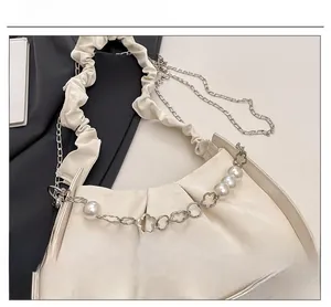 Detail of soft pleated cloud bag with large pearls and silver flower metal chain charm