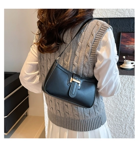 Detailed side view of a black crescent underarm bag with gold buckle on a female model