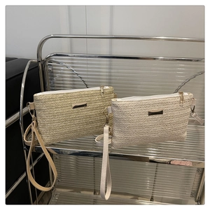 Detail of hand-woven straw clutches showing herringbone texture and zip closure with wristlet