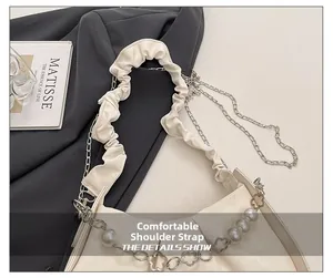 Detail of a creamy white bag showing comfortable ruched strap and pearl chain with flower link