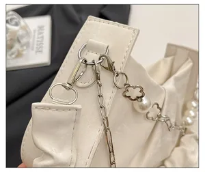 Detail of white pleated leather bag with silver hardware, pearl strap and floral charms