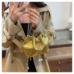 Detailed close-up of a gold textured bucket bag featuring elegant pearl drawstring accents