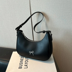 Chic black crescent underarm bag with a silver metal bow accent and smooth leather finish