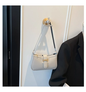 Minimalist light gray crescent underarm bag with gold hardware buckle on a white wall