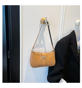 Detail of tan leather baguette bag featuring elegant silver metal buckle and strap