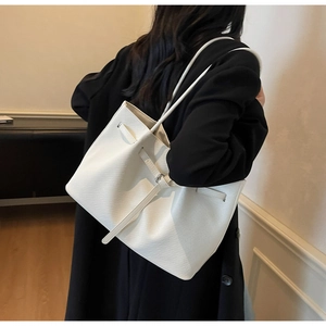 Detailed view of the white lizard-embossed texture on a large French tote bag shoulder strap