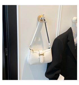 Close-up of white leather crescent bag featuring a golden H-buckle on a wooden hanger