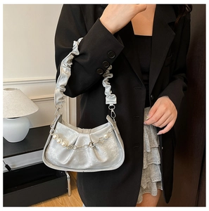 Gros plan du sac hobo argenté avec poignée plissée et détail de chaîne à fleurs perles