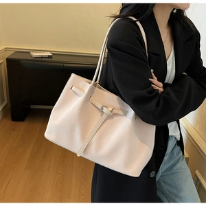 Close-up of a large pale pink textured tote bag with long leather shoulder straps on a model