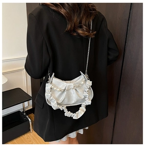 Détail du sac plissé argenté avec chaîne en perles et poignée à volants sur costume