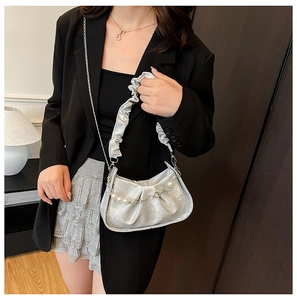 Close-up of a silver pleated cloud bag with elegant white pearl strap and metal chain detail
