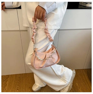 Détail d'un sac plissé rose avec chaîne de perles et texture de cuir élégante