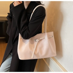 Detail of light pink woven tote bag with adjustable buckle strap and spacious base