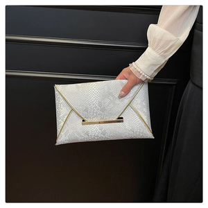 Detail view of silver snakeskin textured envelope clutch with gold metal trim accents