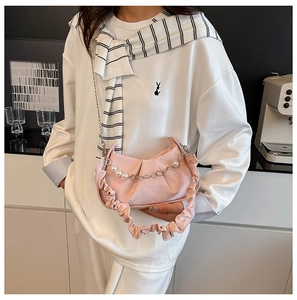 Detailed close-up of pink ruched underarm bag with pearl and heart chain strap
