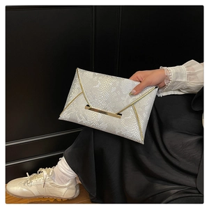 Detail of white snakeskin pattern envelope clutch bag with gold metal trim and texture