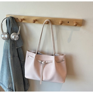 Detail of light pink tote bag with woven texture and decorative metal buckle strap