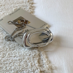 Macro shot of silver metallic mirror handbag with elegant beaded chain on a soft carpet