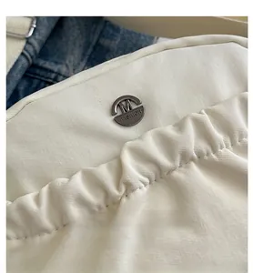 Dettaglio borsa a tracolla in nylon bianco con logo metallico rotondo M FASHION argento