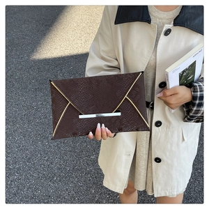 Détail de la pochette enveloppe marron café avec motif serpent et fermoir en métal