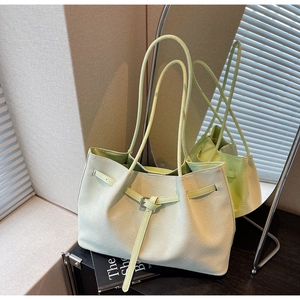 Detail of mint green woven tote bag featuring metal buckle strap and textured finish