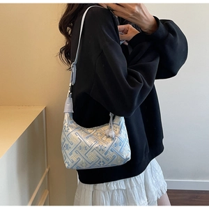 Detailed view of women's shoulder bag with blue floral embroidery and silver hardware