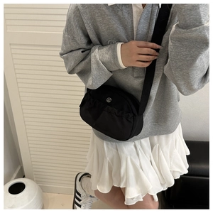 Detail of black nylon crossbody bag featuring pleated front pocket and silver M logo