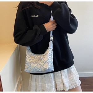 Détail de la broderie chinoise bleu clair sur un sac hobo en forme de croissant