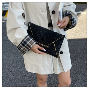 Close-up of black snake pattern envelope clutch bag with gold metallic edge accents