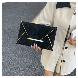 Gros plan sur la pochette enveloppe noire texture serpent avec détails en métal doré chic