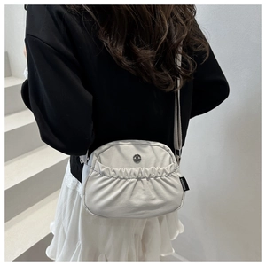 Dettaglio della borsa a tracolla plissettata bianco panna con tasca e logo su modella