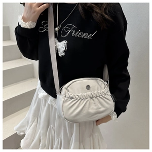 Detail of light beige pleated crossbody bag featuring metal logo and FANYISSA brand label