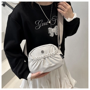 Dettaglio della borsa a tracolla grigio chiaro con texture pieghettata e logo