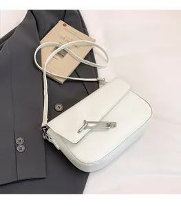 Close-up of a white leather saddle bag featuring a silver T-shaped metal clasp and strap