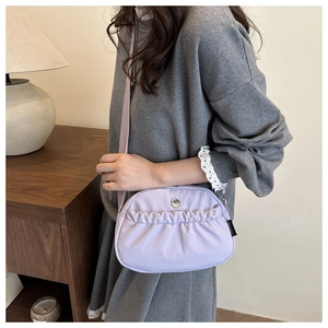 Detail of lavender nylon crossbody bag with pleated texture and round metal logo