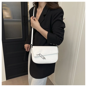 Detail of white minimalist crossbody bag with silver interlocking metal ring buckle on flap