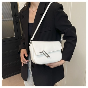Detailed close-up of a white leather saddle bag featuring a sleek silver metal buckle strap