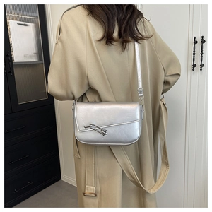 Silver metallic shoulder bag detail showing chain buckle on a khaki trench coat