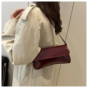 Détail du sac à bandoulière en cuir verni bordeaux montrant la texture brillante