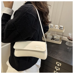 White patent leather baguette shoulder bag shown on model in a modern lifestyle setting