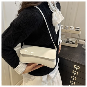 Gros plan d'un sac baguette en cuir verni blanc porté par un mannequin avec style chic