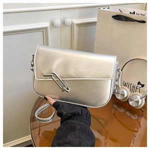 Close-up of silver handbag featuring a decorative large metal safety pin buckle detail