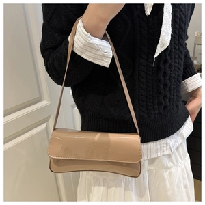Gros plan du sac porté épaule en cuir verni brillant avec détail de base incurvé élégant